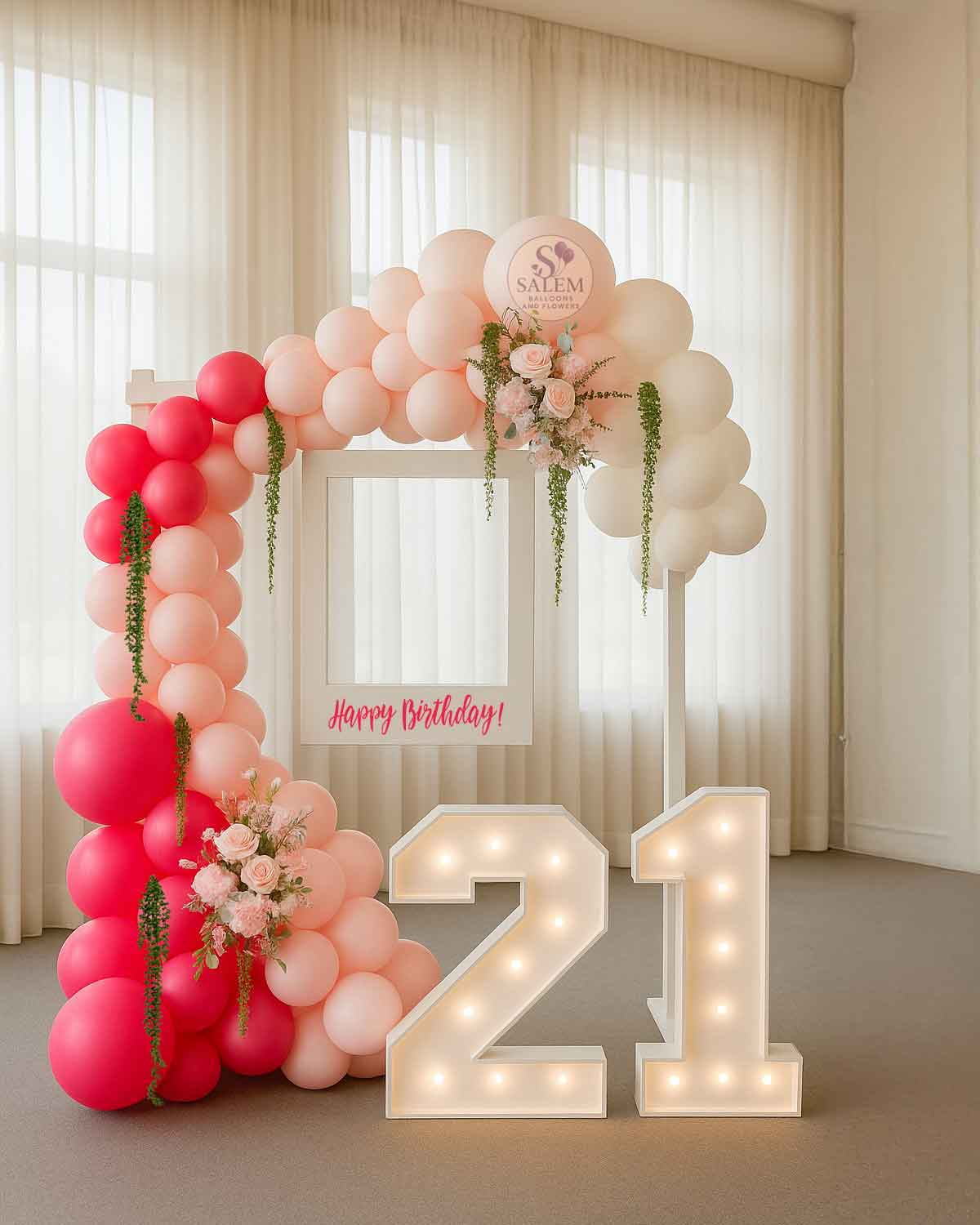 Balloon arch with pink and red balloons and a 'Happy Birthday' Polaroid frame hanging from a white wooden frame with 2 marquee numbers in a room. Balloon Decor Oregon