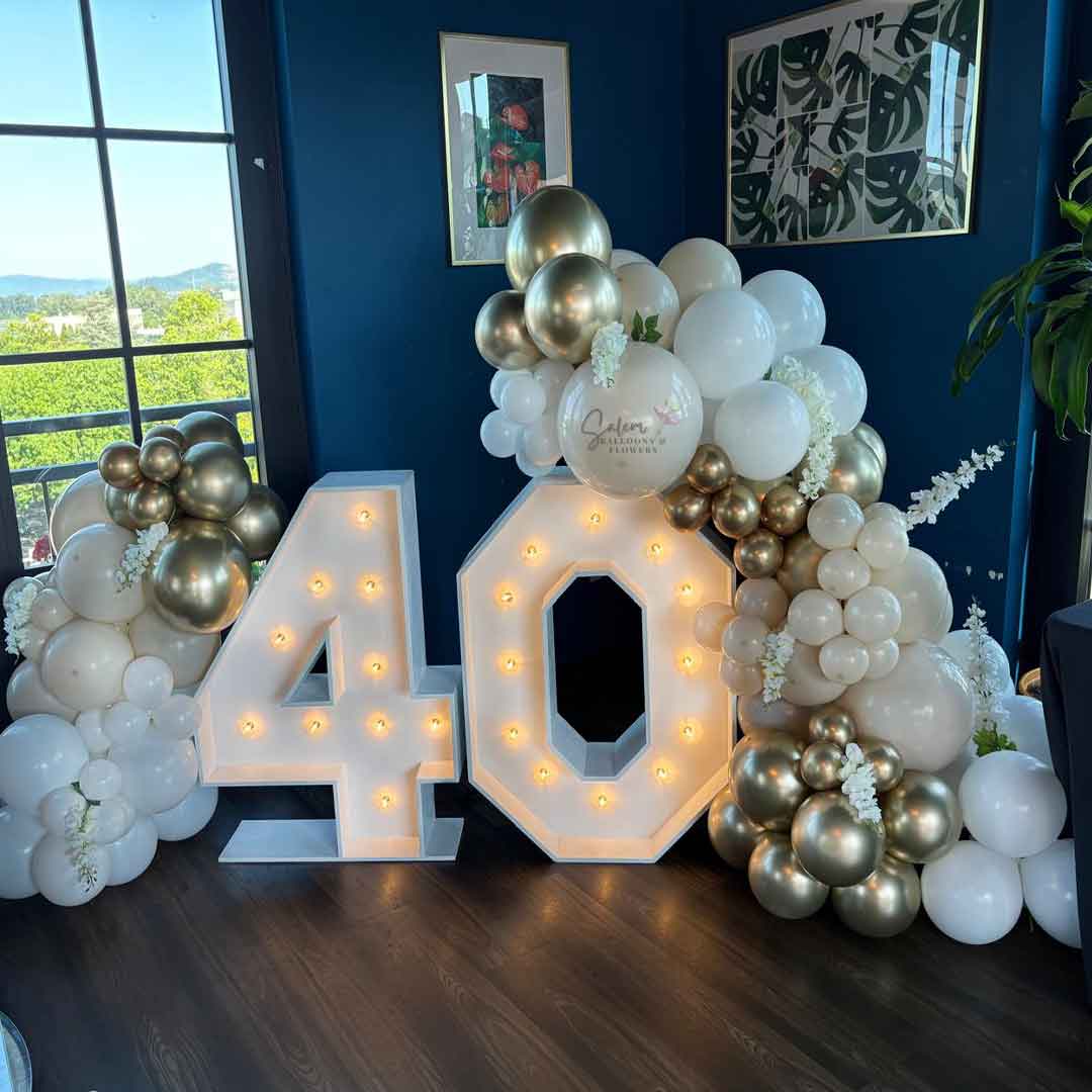 Decorative setup with balloons and illuminated Marquee numbers '40' against a blue wall. Oregon party rental and balloon decor.