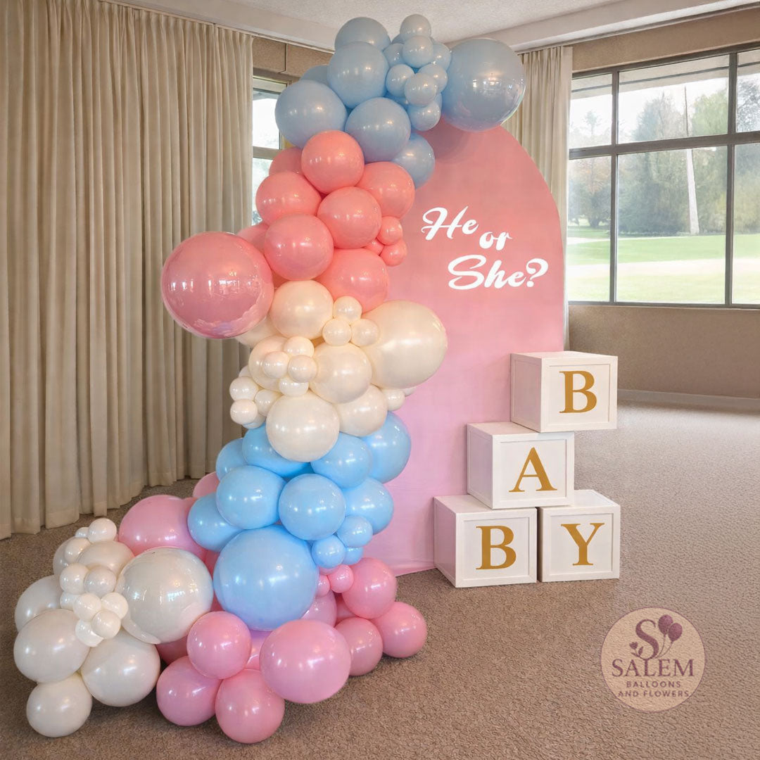 Balloon arch with 'He or She?' + question mark sign, and baby blocks and a pastel blue, pastel pink and cream balloon garland in a room setting. Balloon decor Oregon.