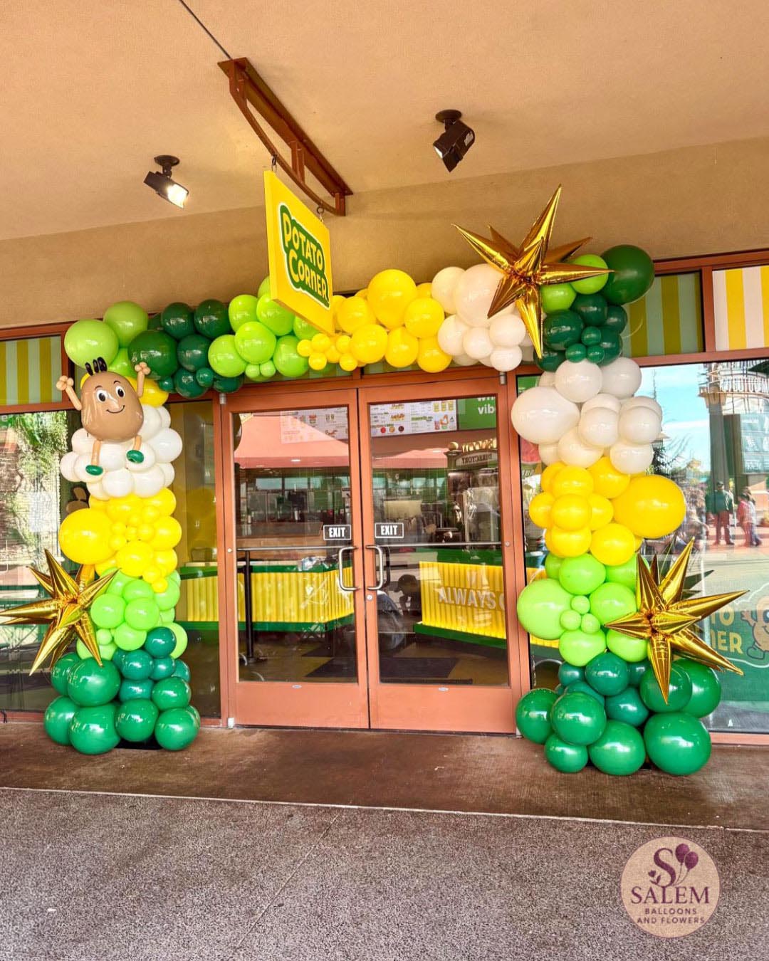 Custom green, yellow and white balloon arch with gold starbursts and handcrafted mascot-inspired sculpture for Potato Corner grand opening at Woodburn Premium Outlets in Oregon.
