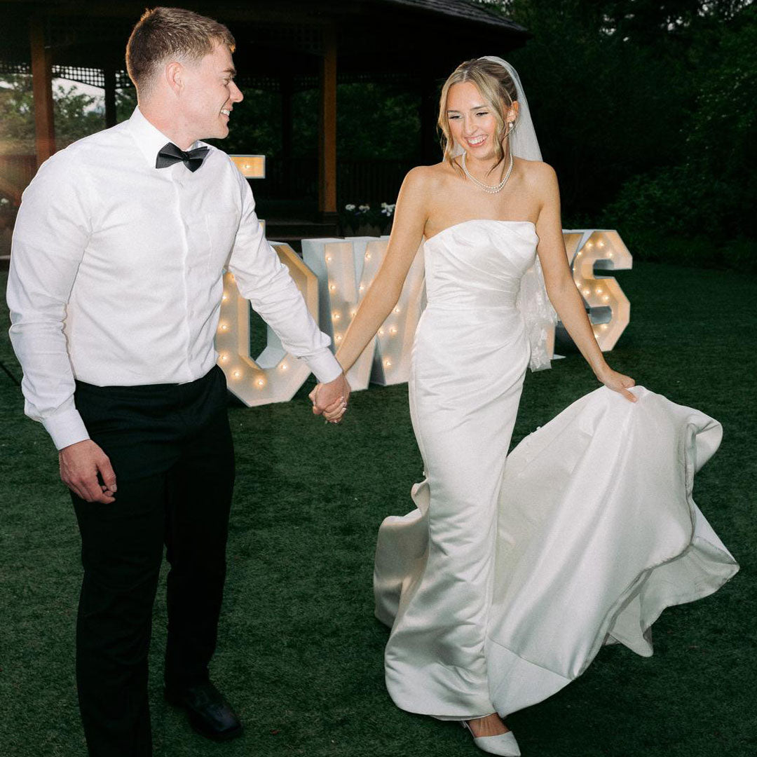Bride and groom sharing a candid moment beside glowing “THE TOWRYS” marquee letters at an outdoor wedding reception in Monroe, Oregon. Elegant wedding decor by Salem Balloons and Flowers.