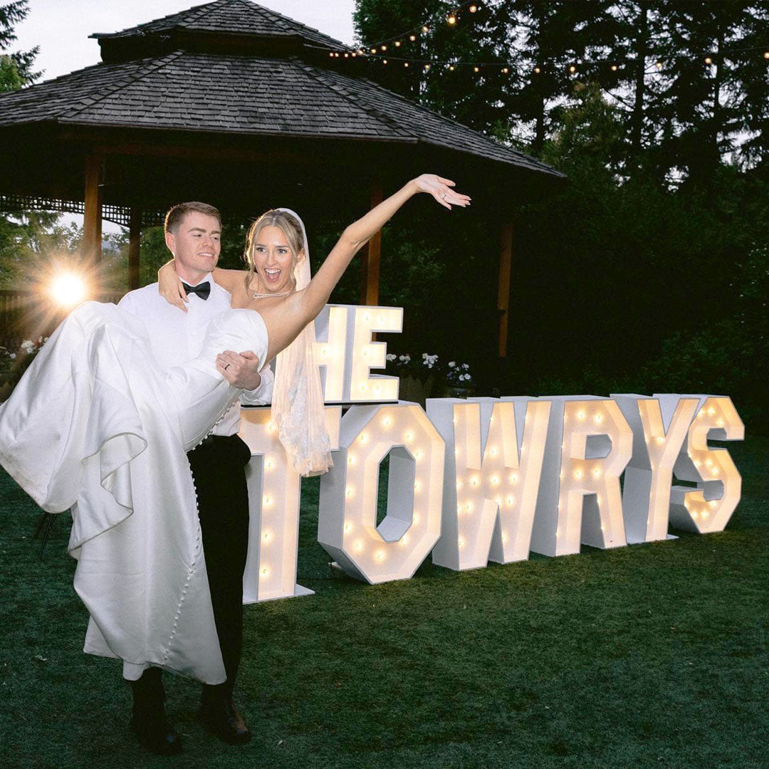 Bespoke 3-foot wooden marquee letter wedding display featuring sharp architectural edges and warm turbo bulb lighting on an outdoor lawn layout. Hand-crafted event rentals by Salem Balloons and Flowers for luxury celebrations in Monroe, McMinnville, and the surrounding Portland metro region.