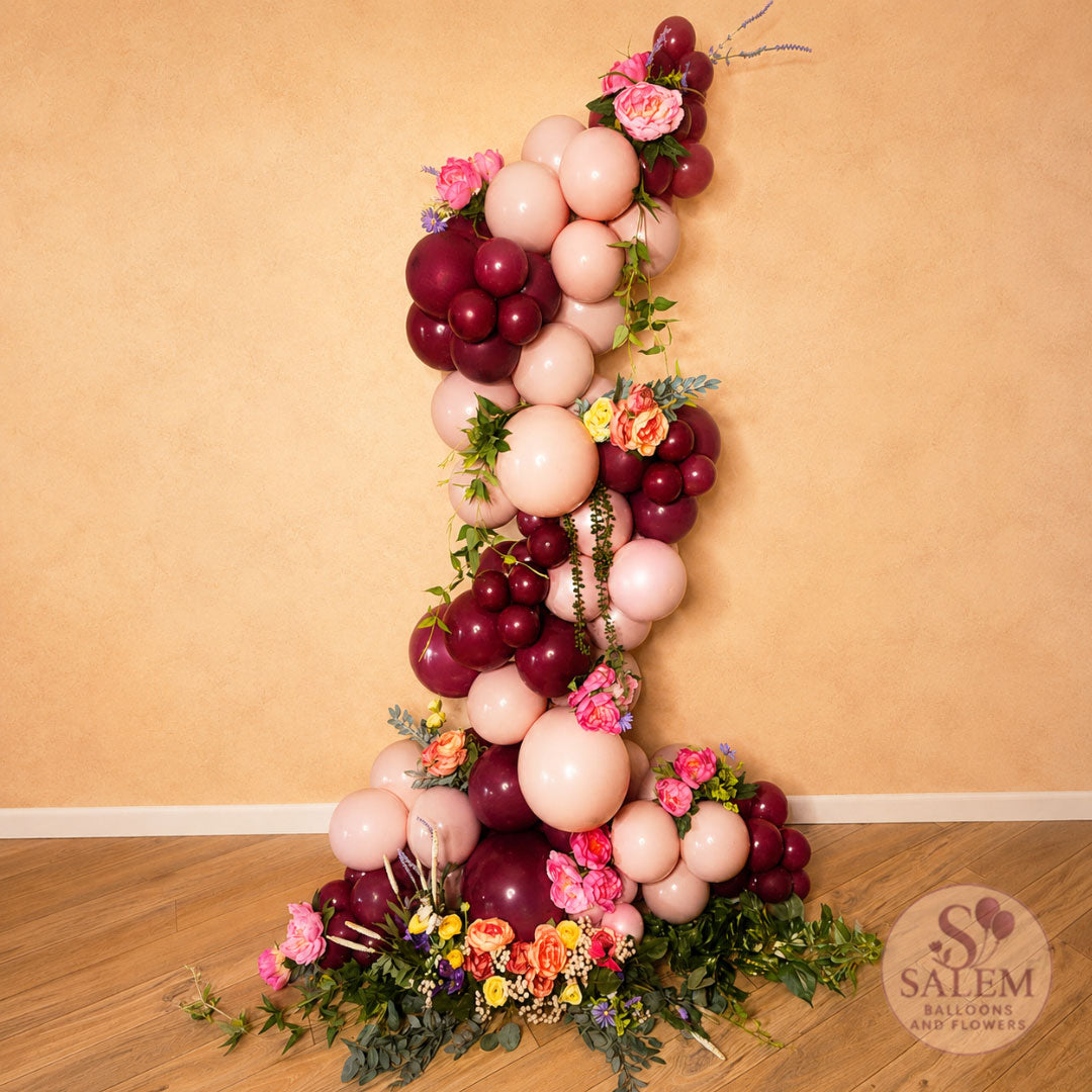Organic balloon garland in a zig zag shape in dusk pink, grape purple and embellished with flowers and greenery ideal for bridal shower, baby shower, birthdays, by Salem Balloons and Flowers.