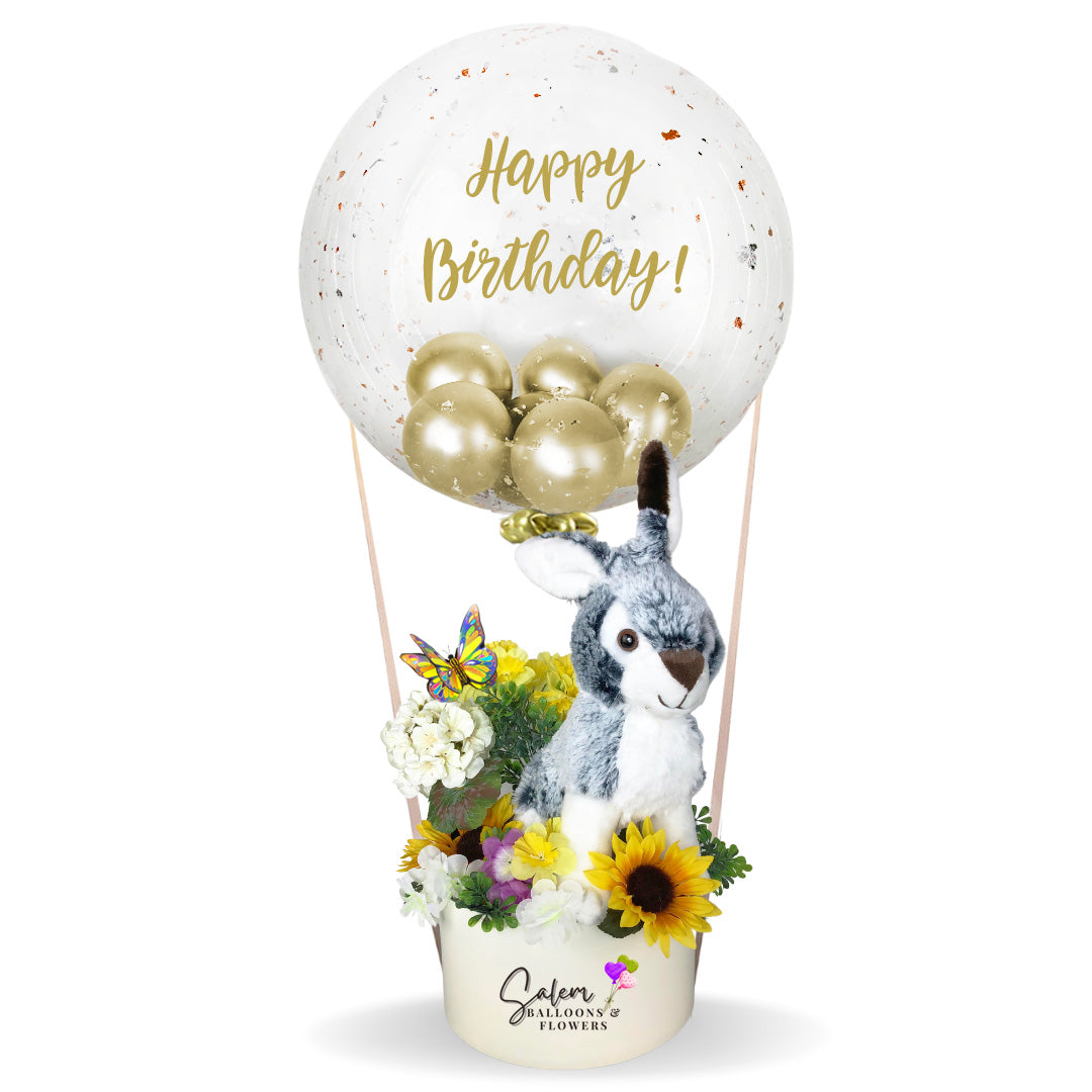 Stuffed bubble balloon gift.  Featuring an adorable furry bunny plush riding a hot air shaped balloon arrangement full of silky flowers. Balloon delivery in Salem OR and nearby cities.