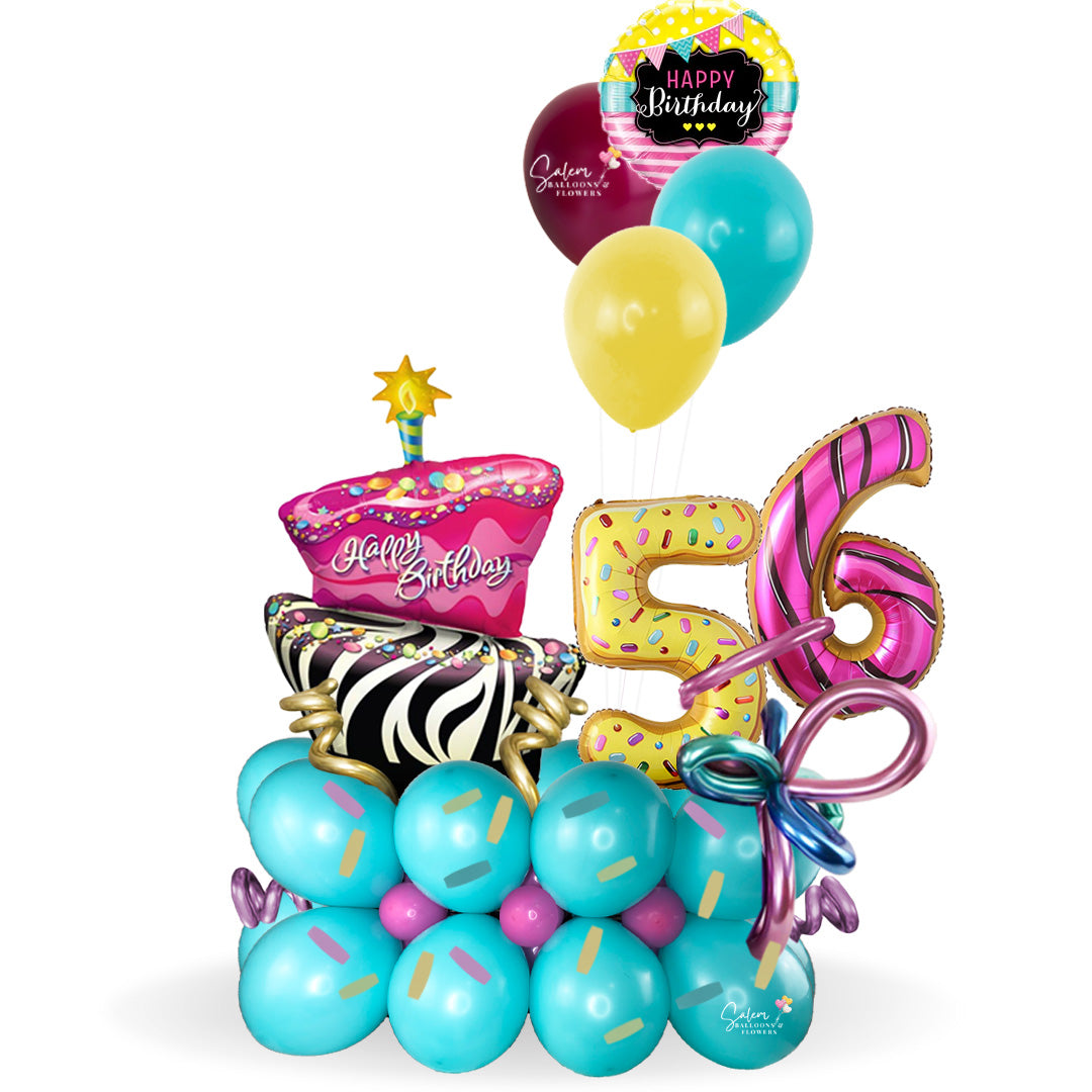 Happy Birthday, balloon bouquet. Featuring a giant gorgeous and funky cake and donuts-shaped balloon numbers on a balloon base decorated with sprinkles and whimsical colorful balloons.