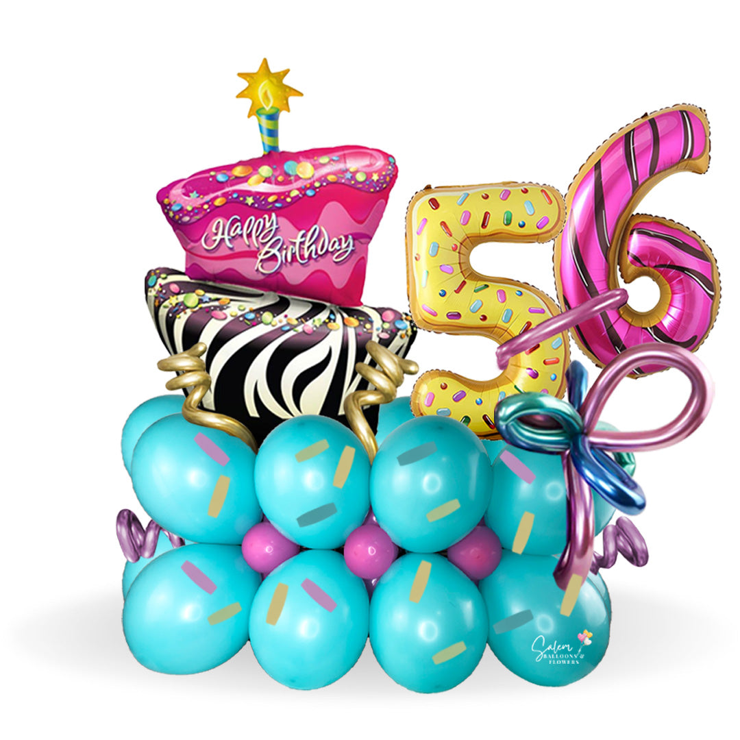Happy Birthday, balloon bouquet. Featuring a giant gorgeous and funky cake and donuts-shaped balloon numbers on a balloon base decorated with sprinkles and whimsical colorful balloons.